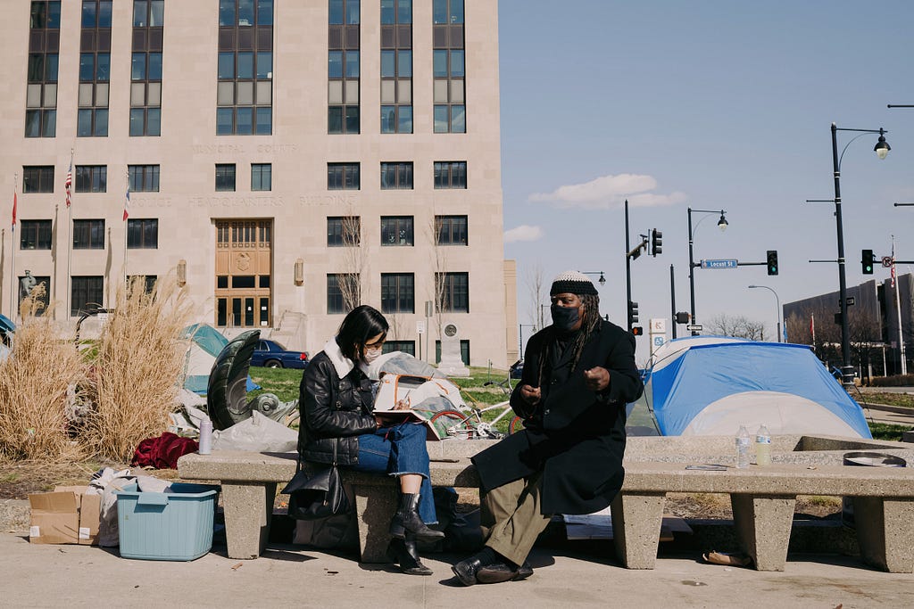 Celisa Calacal interviews a man at a homeless encampment at City Hall in Kansas City.