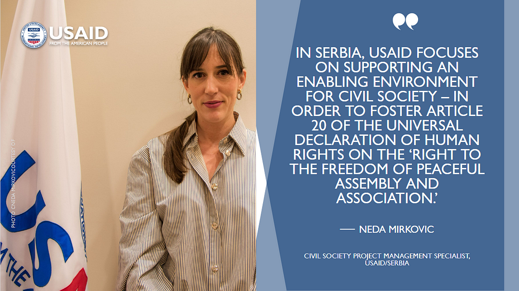 A photograph of a woman posing next to a USAID flag juxtaposed with a graphic that quotes her saying: “In Serbia, USAID focuses on supporting an enabling environment for civil society — in order to foster Article 20 of the Universal Declaration of Human Rights on the ‘Right to the freedom of peaceful assembly and association.’”
