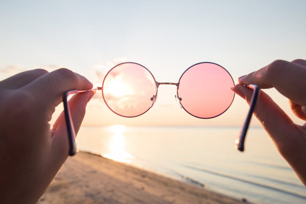 rose-colored glasses looking into a sunset on a beach