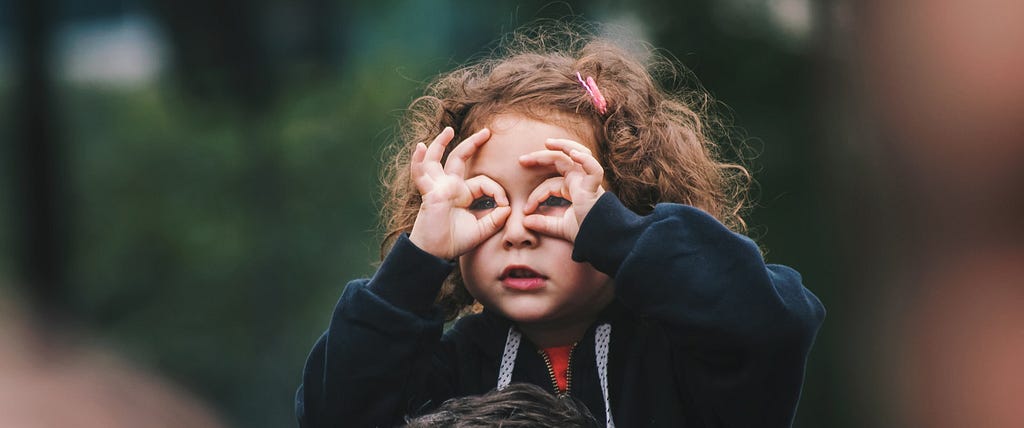 Little girl making a binoculars shape with her hands, as an analog for looking into the future