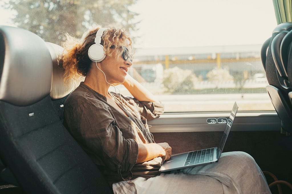 Woman in front of a laptop listening with headphones.