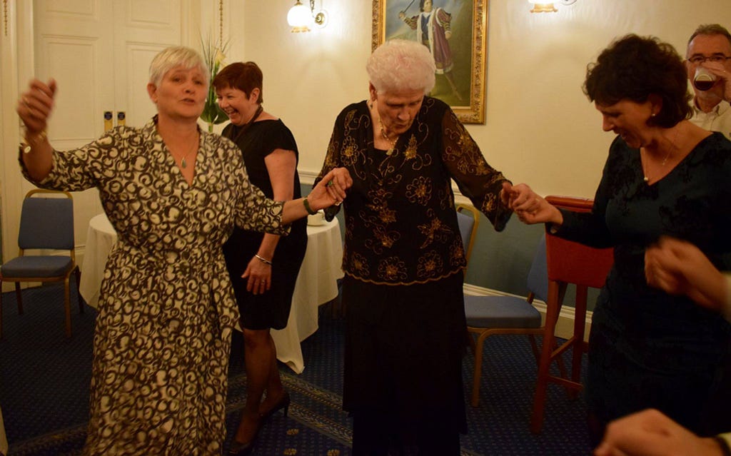 granny dancing holding the hands of two of her daughters