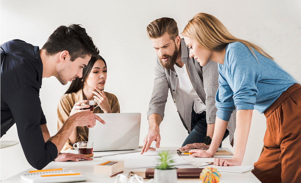 Four young, attractive, office workers looking at a document on a conference room desk