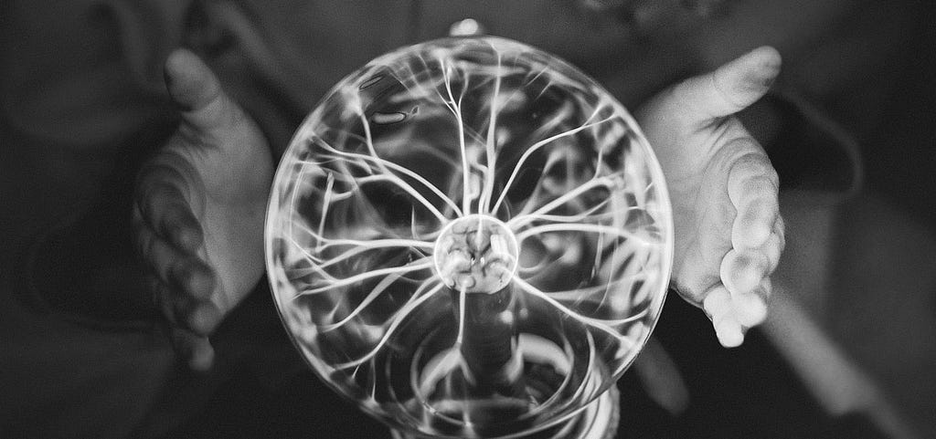 glass ball with electricity eminating to the outside toward a pair of hands. Image by rawpixel.com