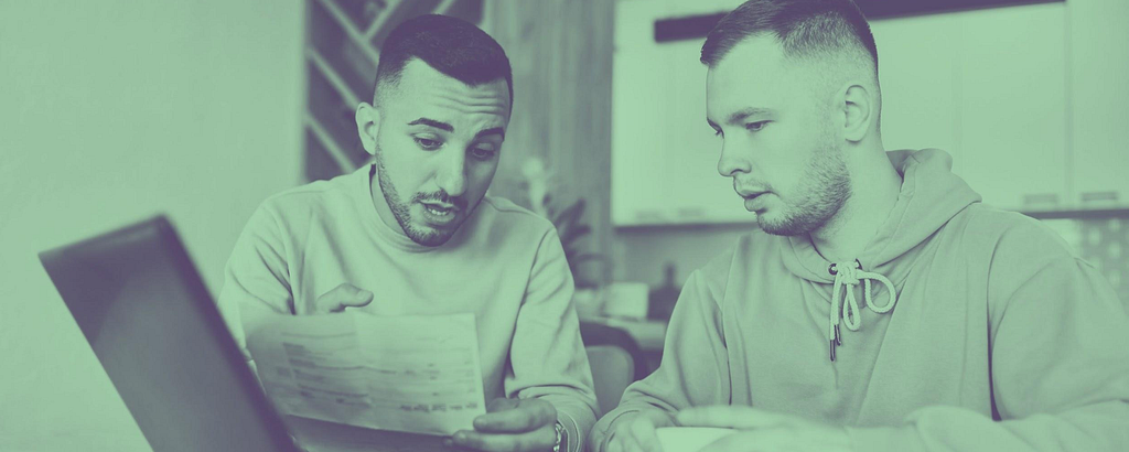 Image shows 2 men looking at their energy bills and discussing them.