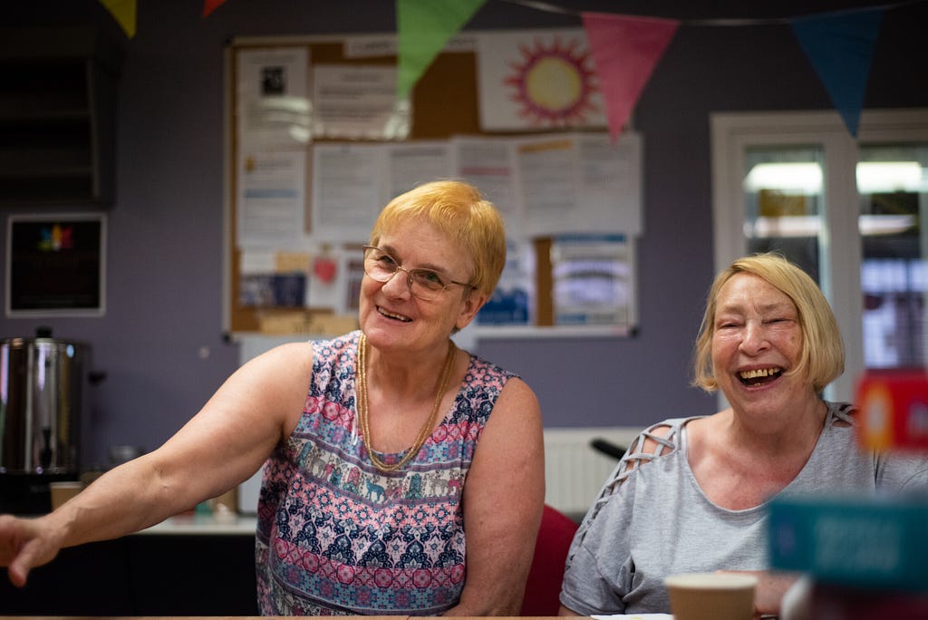 Two older women participating in a discussion, sharing a joke and laughing