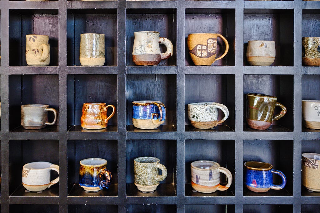 A lot different types of mugs, presented in a cupboard together