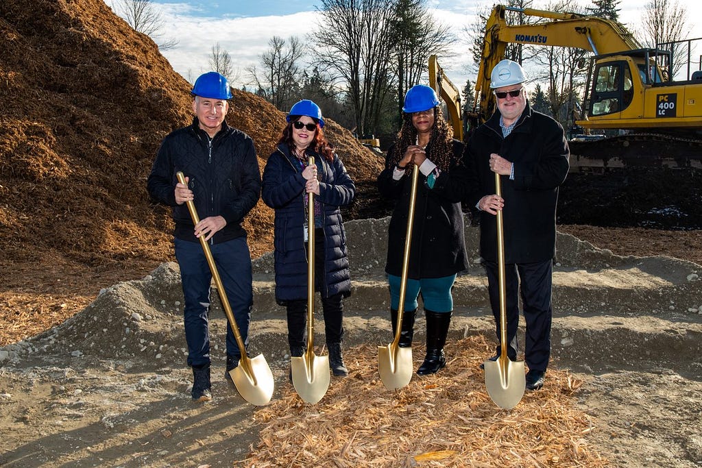 Executive Constantine and community leaders hold shovels at a construction site for a groundbreaking of an affordable housing project.