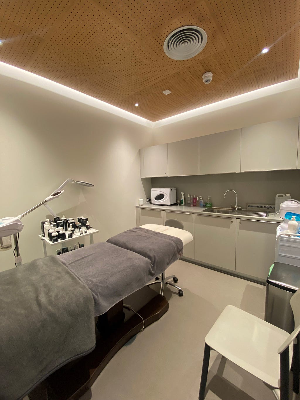 A beauty treatment room with a bed in the middle, and skin care treatments next to the bed.