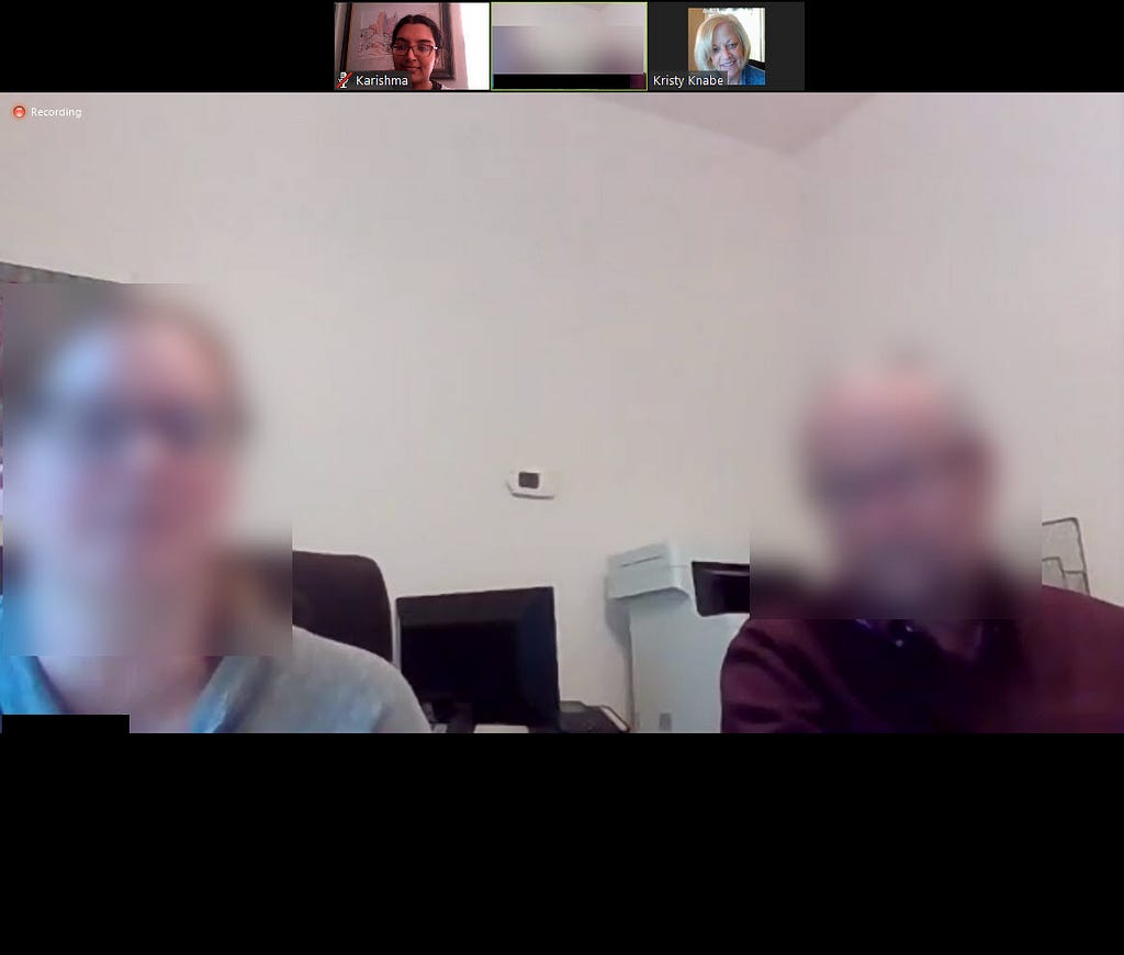 Screenshot of a conference call. Large view of 2 people, faces blurred. At the top is a small view of the 2 researchers.