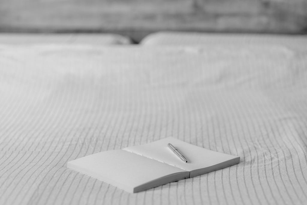 Empty agenda with pen on bed in house