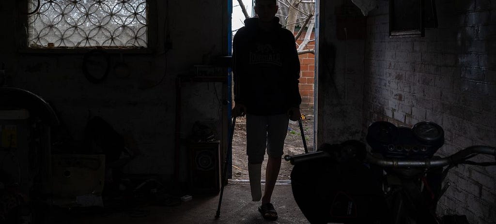 A person who lost a foot walks through a door with crutches.