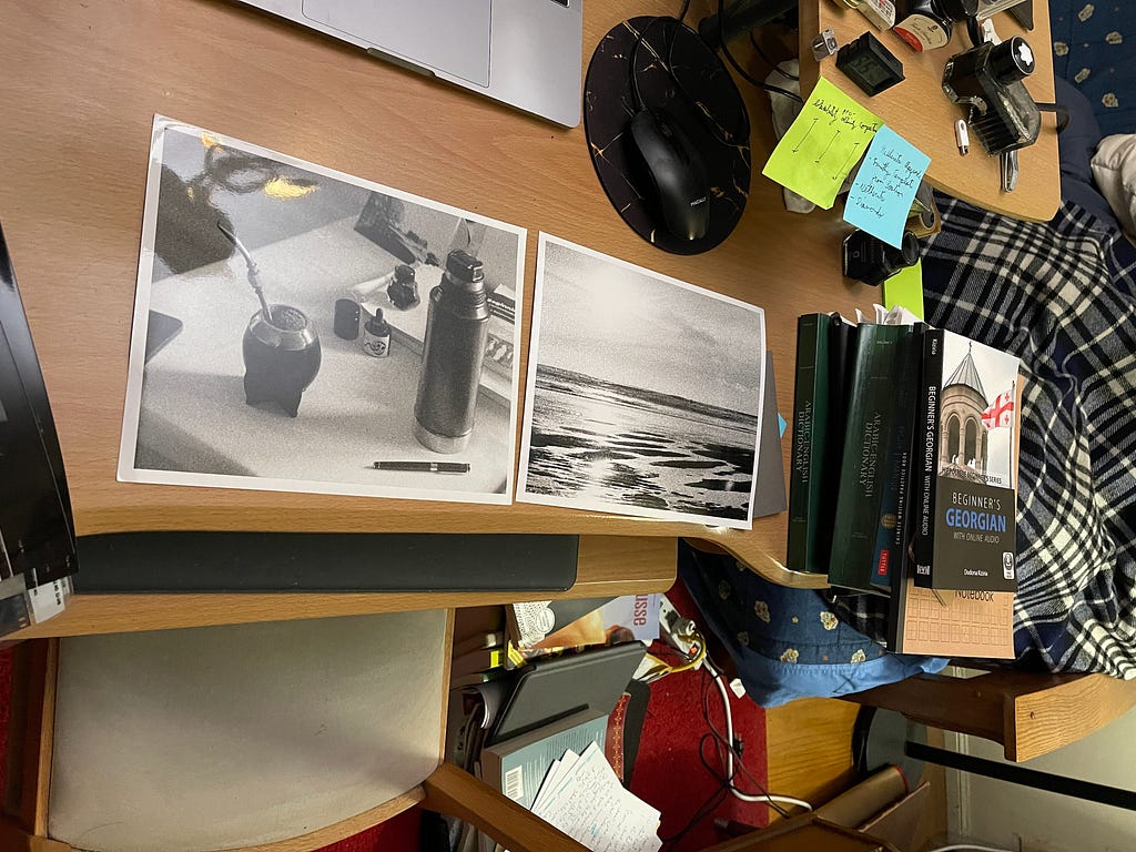 A photo of two black and white prints on a wooden desk made by the author