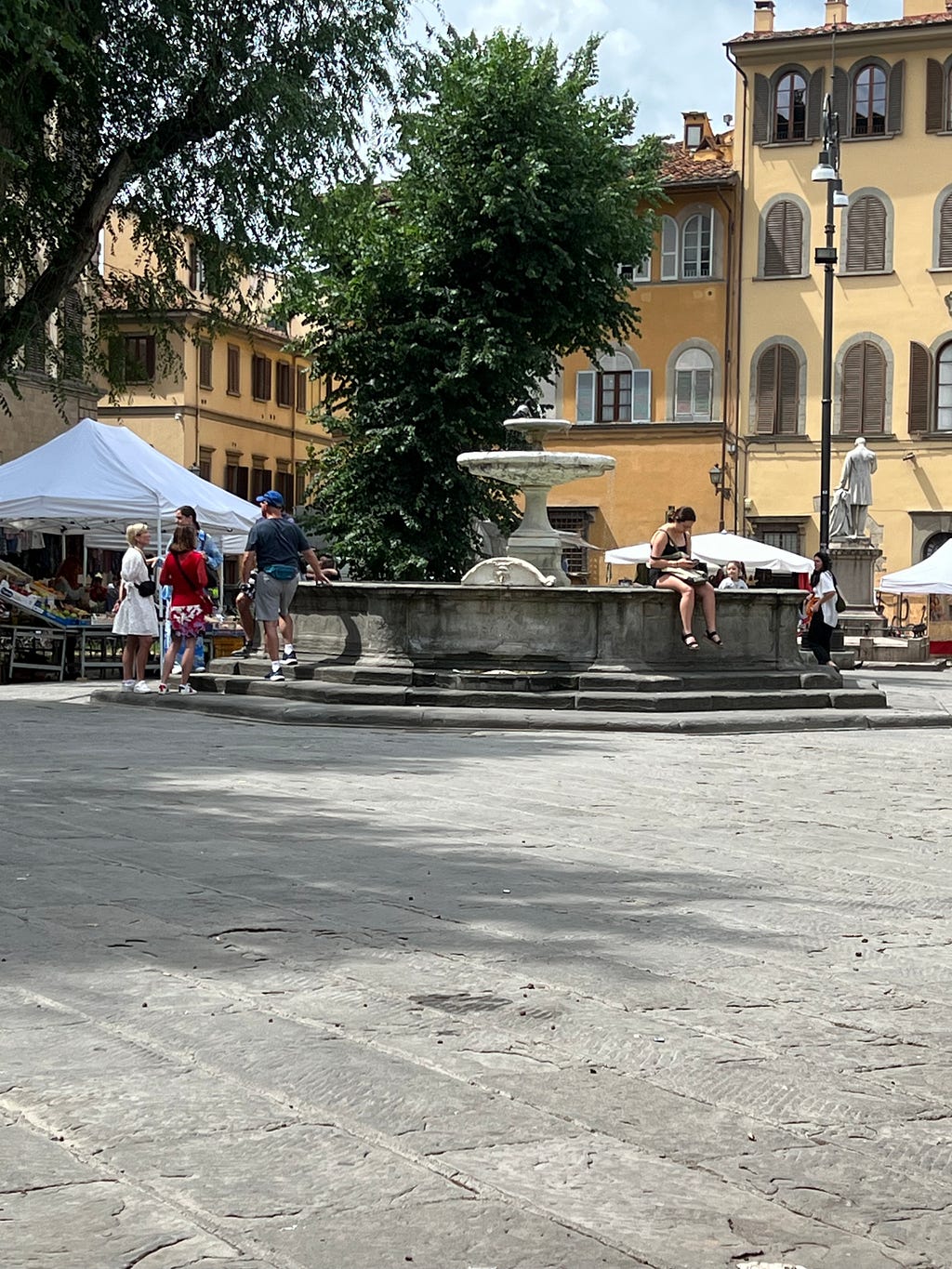 Photo of people gathered around a fountain in the Piazza Santo Spirito