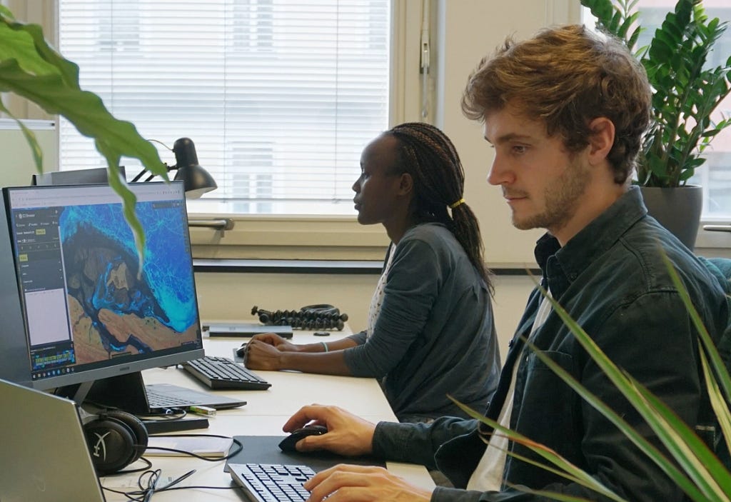 Two colleagues from Sentinel Hub Austria working on a computer.
