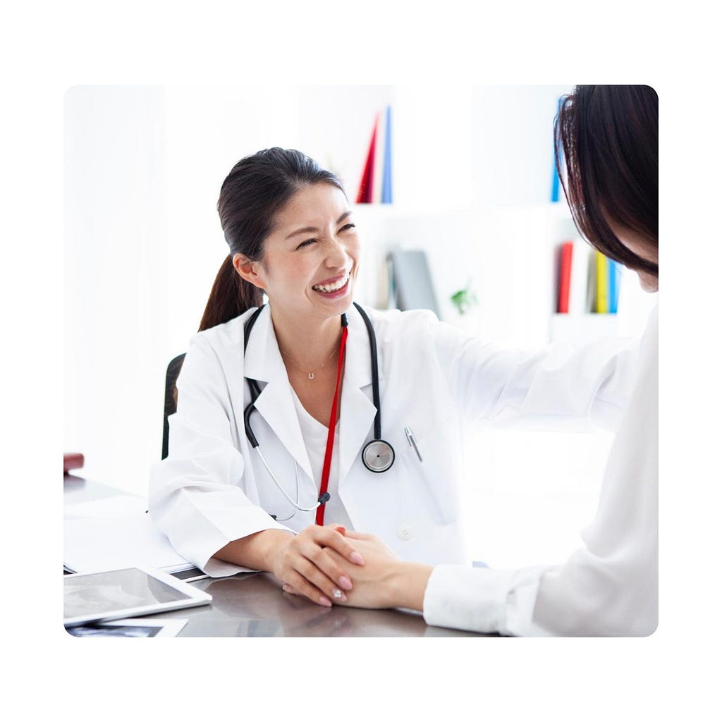 Picture of a female doctor smiling with the hands on the shoulder of another person.