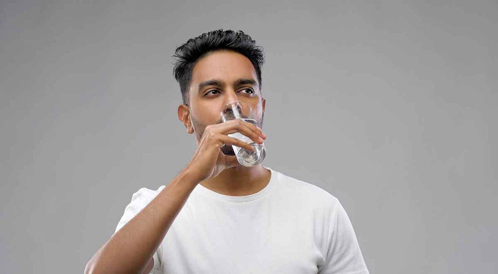 A man casually sipping water during his water fasting