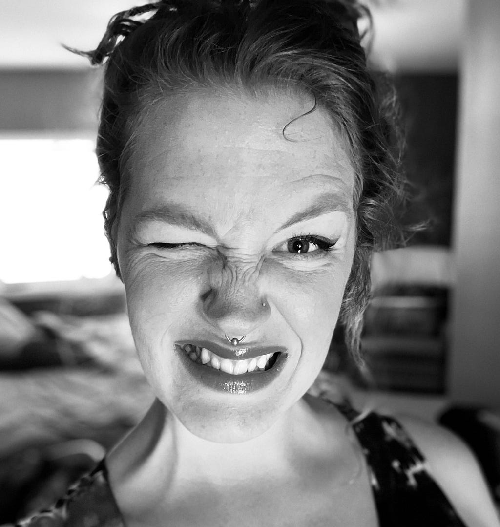 Tegan Kraklio, smiling and winking. Photo in black and white.