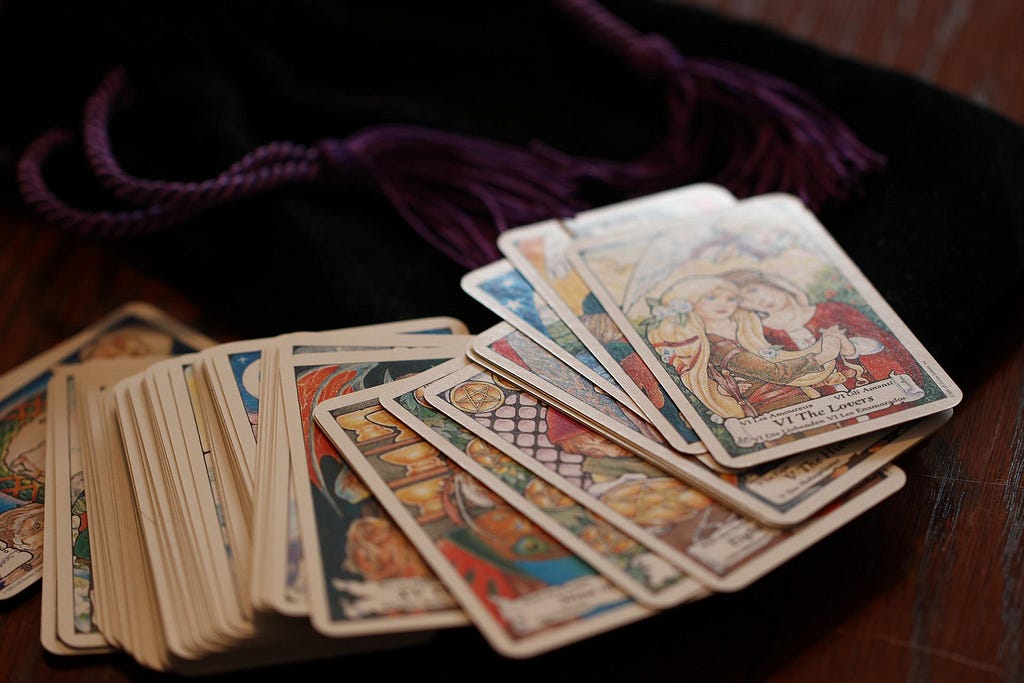 Tarot cards lay spread out on a wooden table.