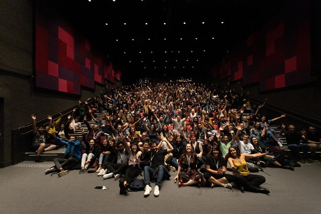 Participantes do WIAD-SP levantando braços e mãos e sorrindo para a foto