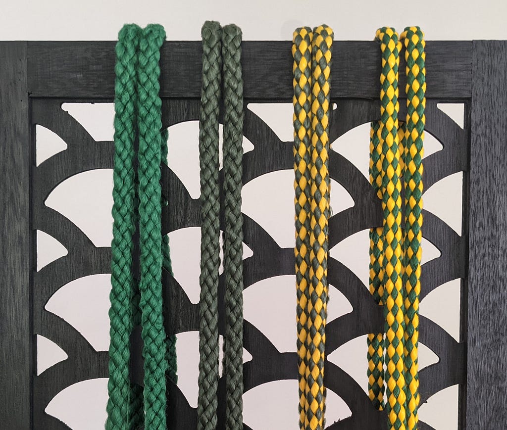 4 capoeira belts ranging from green to green and yellow in order of level.