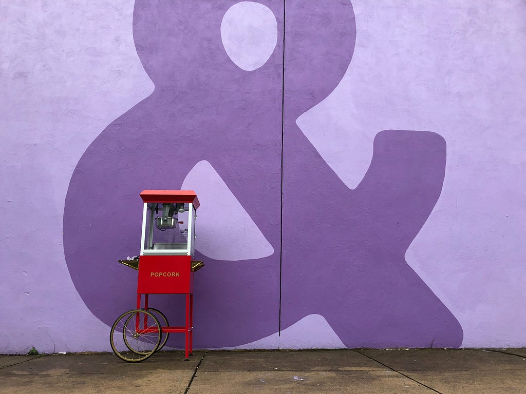 Popcorn cart against a dark purple wall.