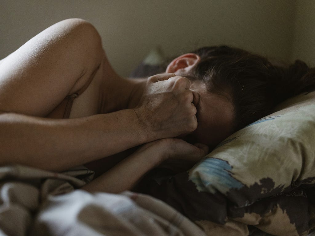 a woman laying in bed with her head on a pillow