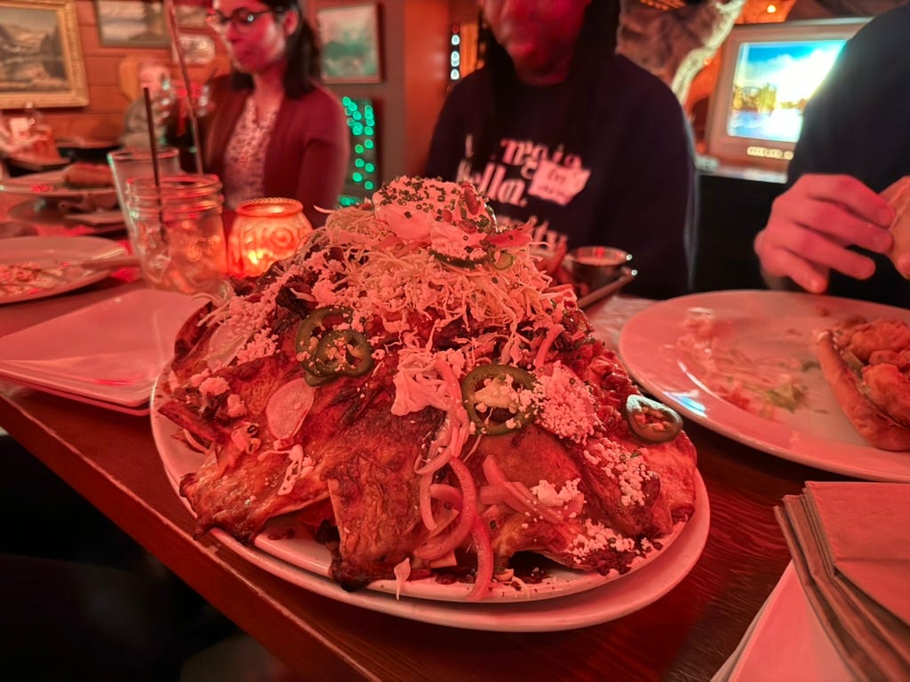 A very large plat of nachos at a table with new faculty and other food.