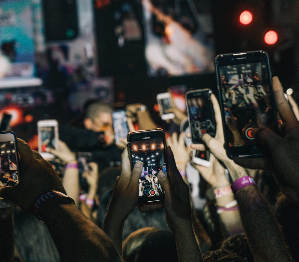 Concert spectators holding up a lot of smartphones to capture the moment