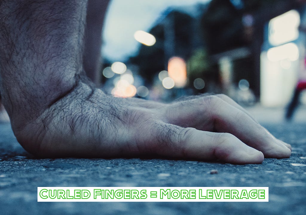 How to instantly improve your handstand with curled fingers. A photograph of hands with curled fingers touching the ground.