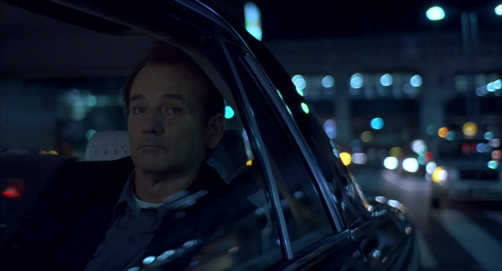 Bill Murray, a white man in a car at night, gazing out the window with a vacant look.