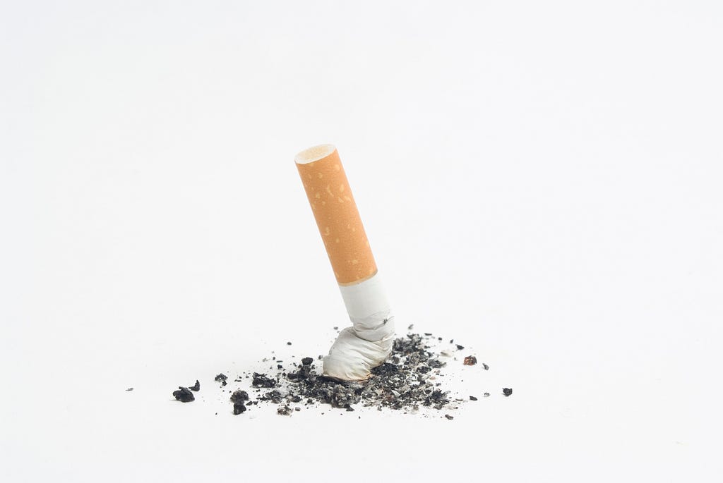 a cigarette being stubbed out into a pile of ash on a white background