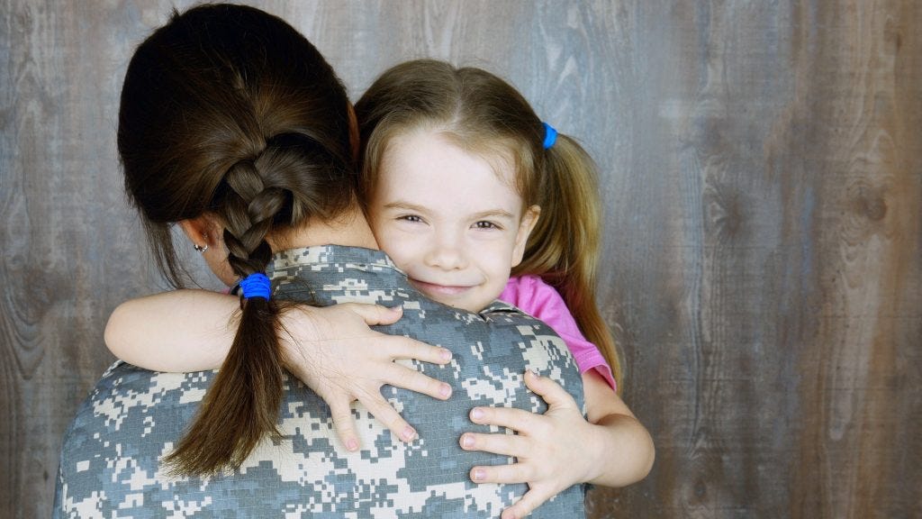 Female U.S. soldier hugging their young daughter.