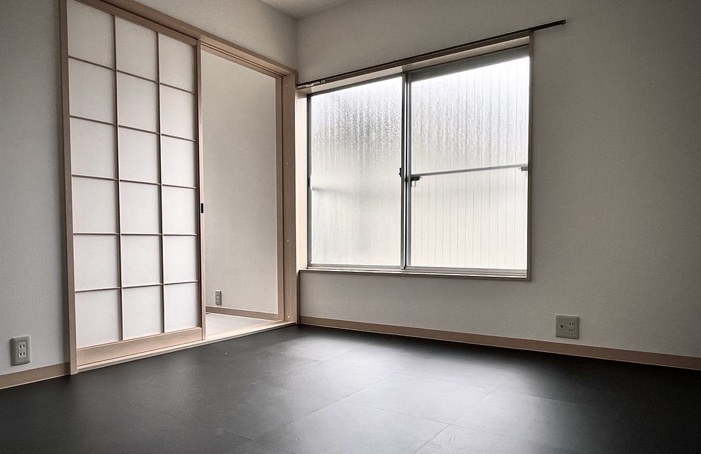 An empty room with a Japanese-style screen door and a large window to the balcony