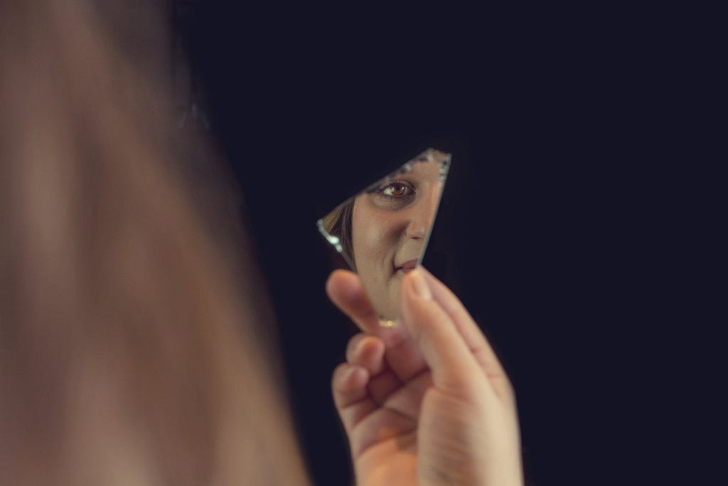 Person Holding a Piece of Broken Mirror with Reflection