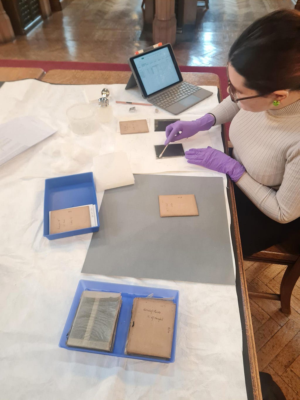 Iris sitting at a desk wearing purple gloves, cleaning a glass plate [Image credit: Laura Snow]