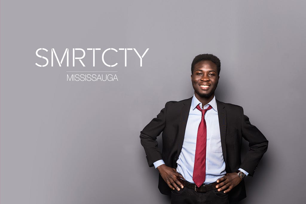 A man in a suit standing with his hands on his hips. There is a smart city Mississauga logo beside him.