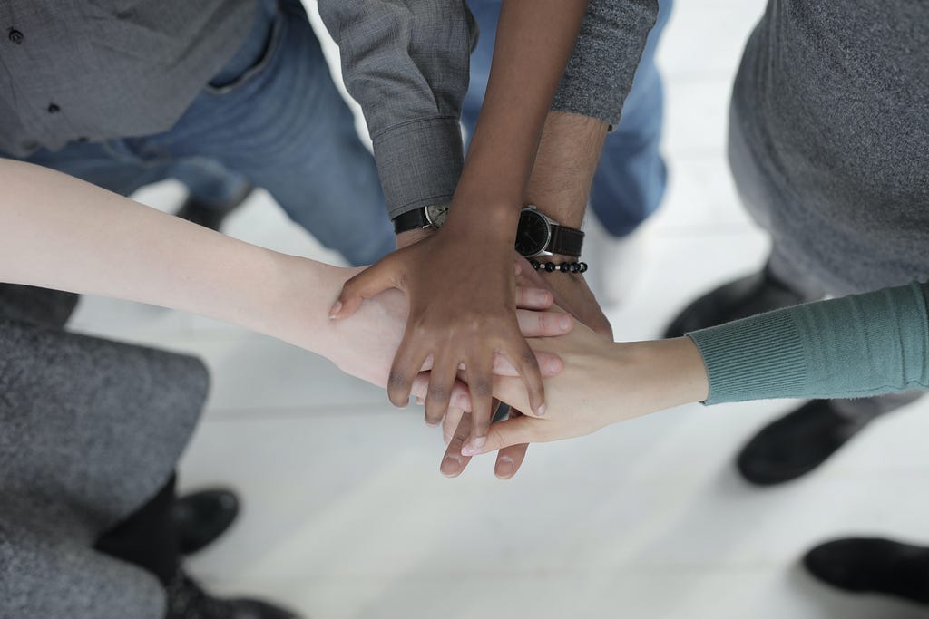 Unrecognizable multiethnic colleagues joining hands