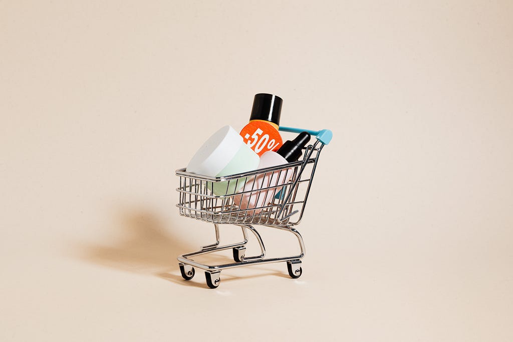 Different sized product bottles sit inside a toy shopping cart.