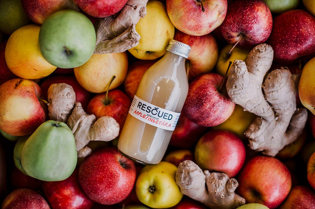 A bottle of Rescued juice among fresh apples and ginger