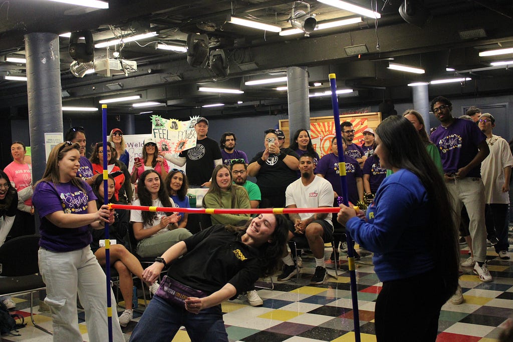 Teams cheer on a team member as she dives under the limbo bar