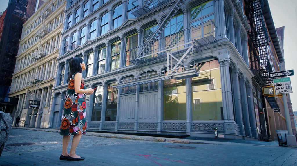 Yukie Ohta, founder of the SoHo Memory Project stands in front of the Judd Foundation in SoHo, New York City, while listening and experiencing her SoHo audio walking tour.