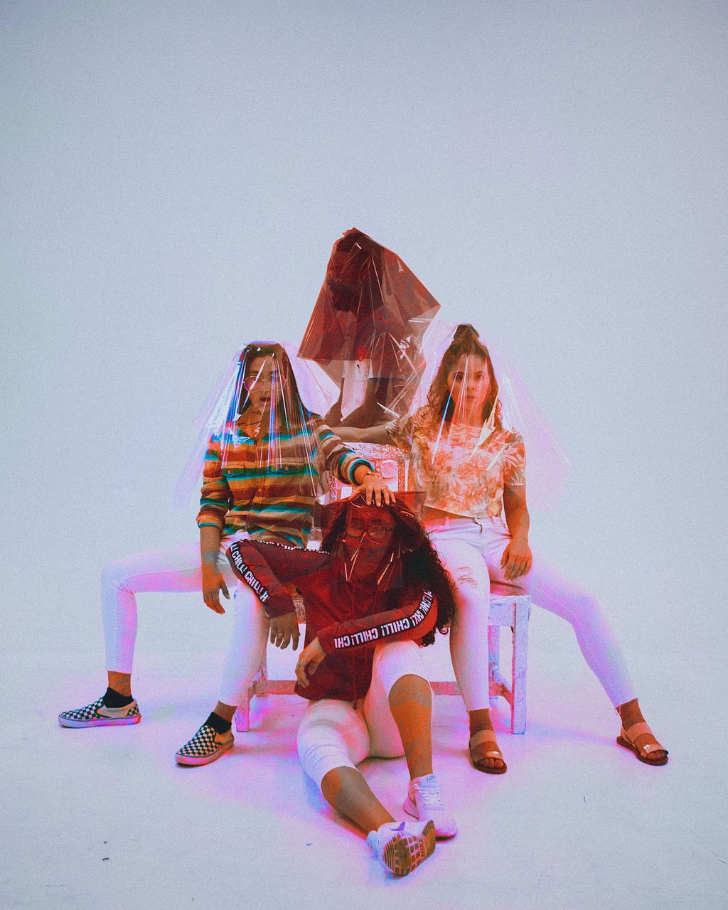 Four young people pose with interesting plastic sheeting over their faces.