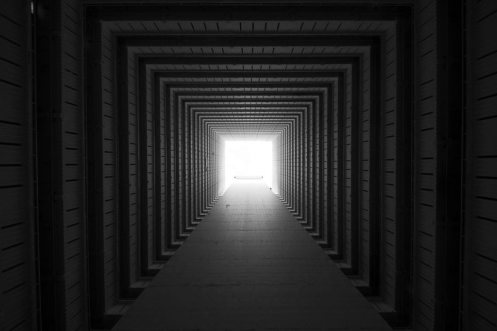 square tunnel with a light at the end