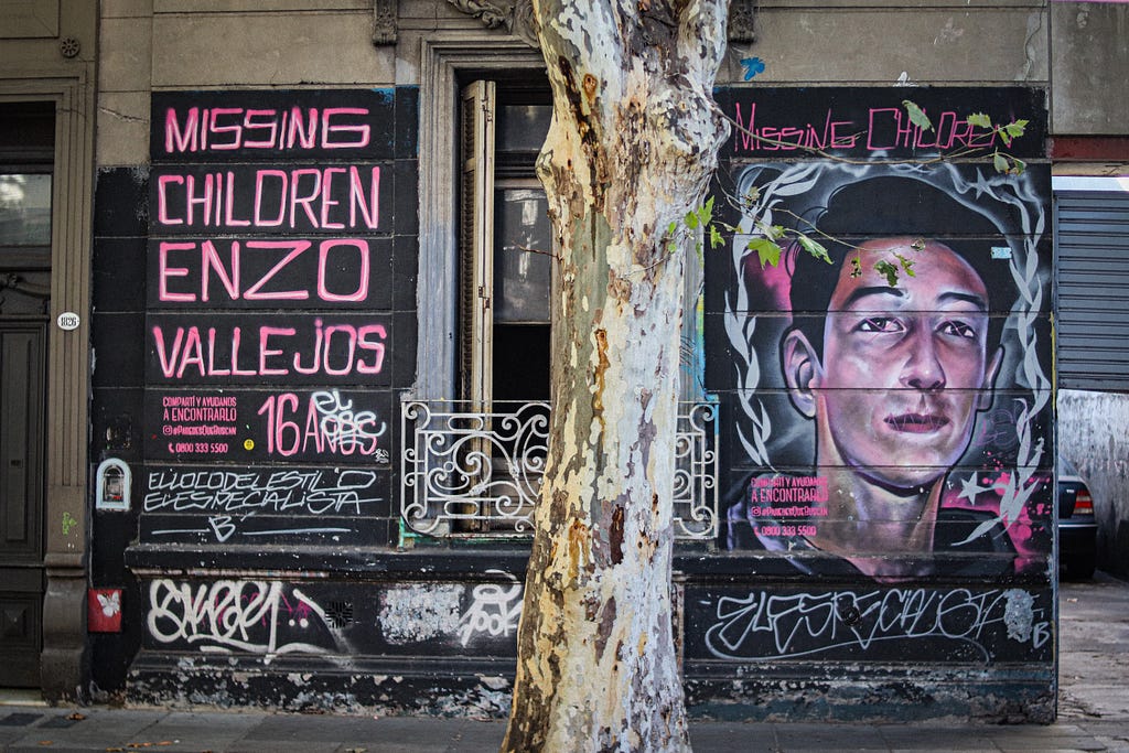 Parede com grafite dizendo "Missing Children, Enzo Vallejos" e a imagem de um menino