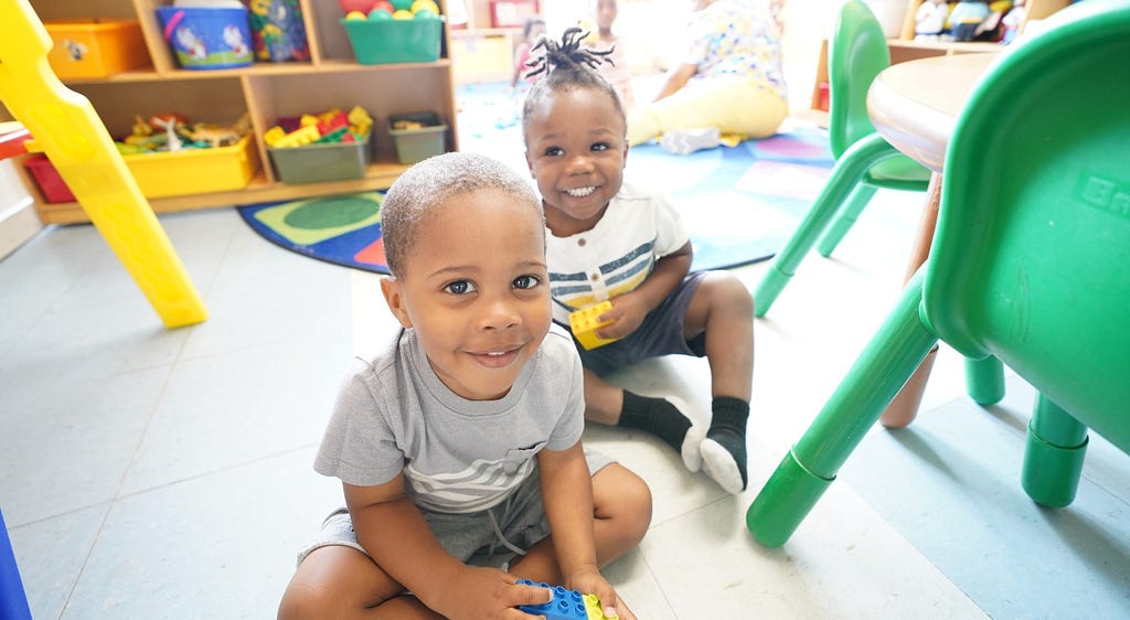 Two children play with blocks in a sunny child care classroom