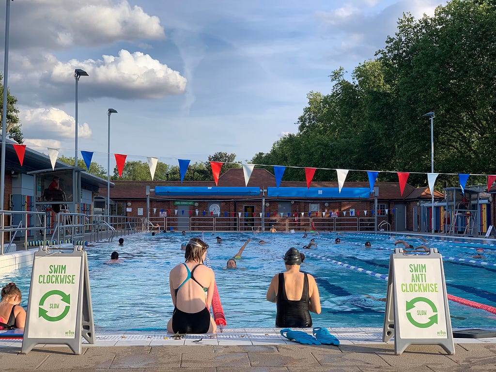 Two women taking a rest in London Fields Lido swimming pool in the summer.
