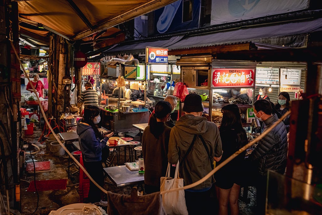Customers standing around a Taiwanese night market stall
