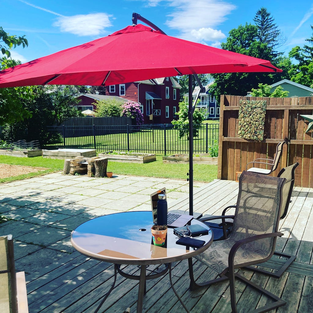 Outside table and chair with shade umbrella and computer on table