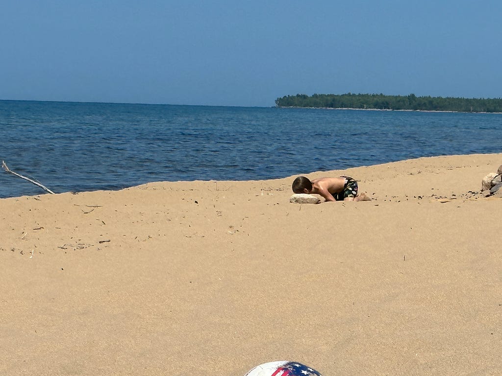 Small boy resting on the sandy beach of Lake Superior